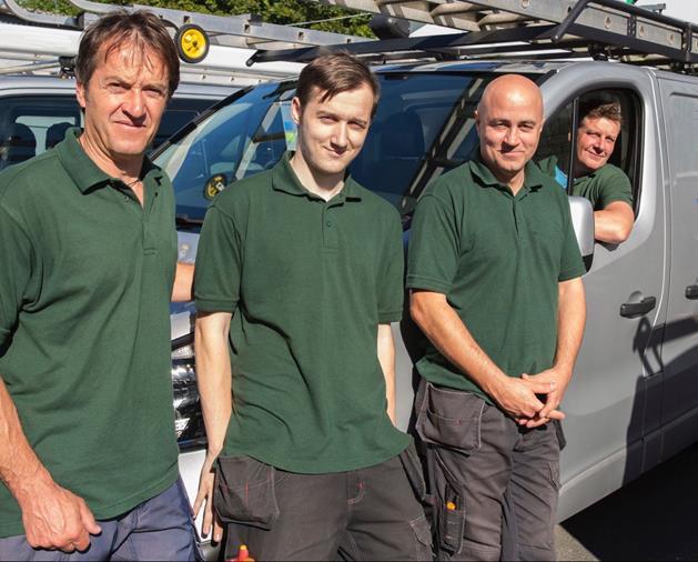 three men in green polos standing in front of ADA van with a fourth man in driver's seat