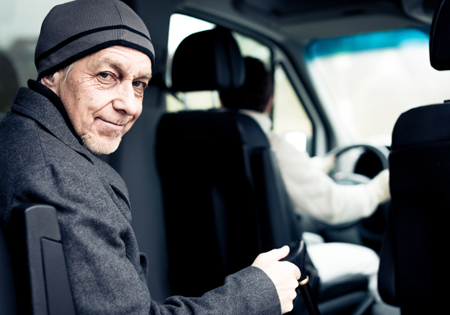 elderly man sitting in back of ADA vehicle being driven by second man